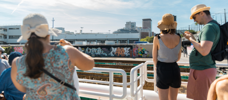 Passengers of a cruise on the Canal de l'Ourcq take photos of street art from the top of the boat