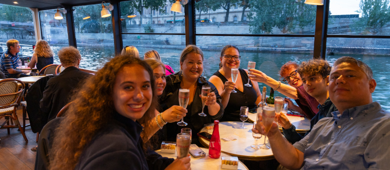 Groupe célébrant avec du champagne lors d'une croisière sur la Seine.