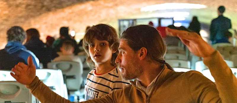 Crew sharing the history of the Canal Saint-Martin with children during a cruise under the vault